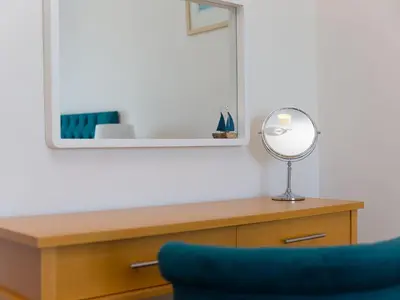 a room with a desk with a mirror and a blue chair at Skysail in St Ives