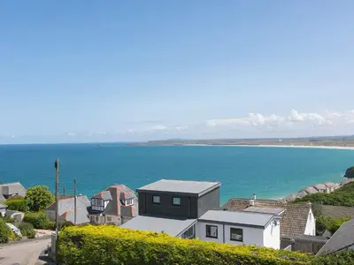 a house on a hill next to a body of water at Skysail in St Ives
