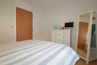 a bedroom with a bed and a dresser and a mirror at 13 Clock Tower Court in St Austell