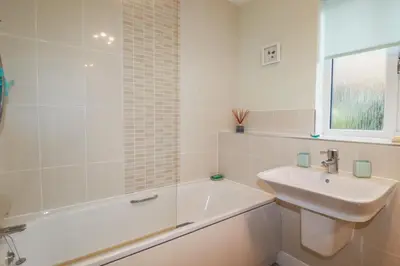 a white bathroom with a sink and a bath tub at 13 Clock Tower Court in St Austell