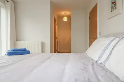 a white bed with a blue towel on it at 13 Clock Tower Court in St Austell