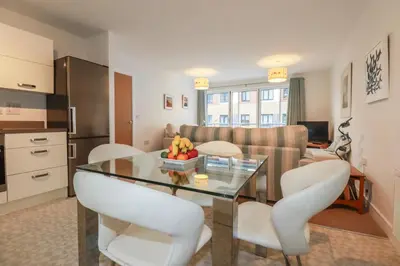a living room with a glass table and white chairs at 13 Clock Tower Court in St Austell