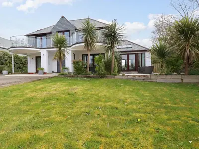 a house with palm trees in front of a yard at Goatsland in Wadebridge