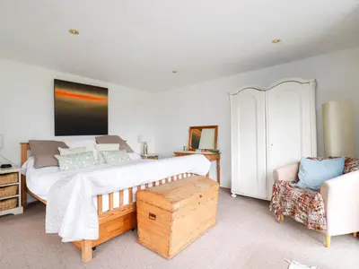 a bedroom with a large bed and a chair at Goatsland in Wadebridge