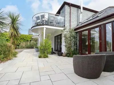 a patio with chairs and a balcony on a house at Goatsland in Wadebridge