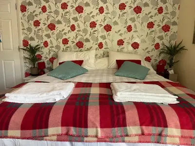 a bed with two pillows and a red and green blanket at Cornerways Guest House St Austell Cornwall in St Austell