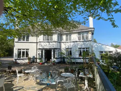 a white house with tables and chairs in front of it at Cornerways Guest House St Austell Cornwall in St Austell