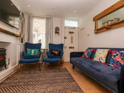 a living room with a blue couch and two chairs at Seahorse Cottage in St Ives