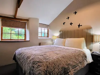 a bedroom with a large bed with birds on the wall at 2 bed barn on smallholding in Stithians