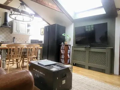 a living room with a large television and a table at 2 bed barn on smallholding in Stithians