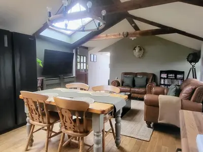 a dining room with a table and chairs and a couch at 2 bed barn on smallholding in Stithians