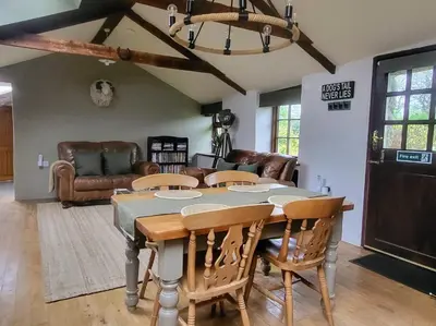 a dining room with a table and a couch at 2 bed barn on smallholding in Stithians