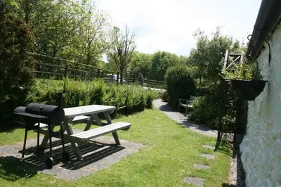 a picnic table with a grill in a garden at 2 bed barn on smallholding in Stithians