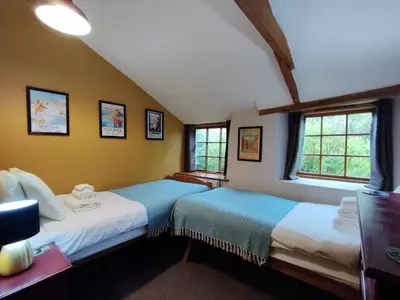 two beds in a room with two windows at 2 bed barn on smallholding in Stithians
