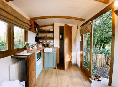 a kitchen in a tiny house with a large window at Dowr-Gwel Shepherds Hut in Saint Cleer