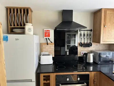 a kitchen with a stove top oven next to a refrigerator at Character 3 Bed Cottage, Close to Waters edge, Parking in Looe