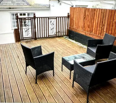 a patio with chairs and a table and a fence at Character 3 Bed Cottage, Close to Waters edge, Parking in Looe
