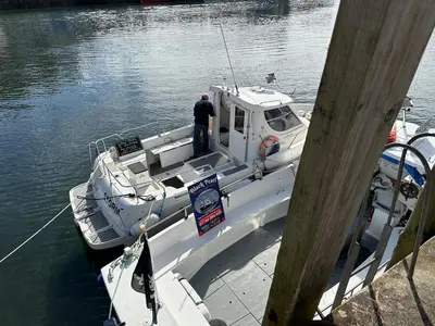 a man standing on a boat in the water at Character 3 Bed Cottage, Close to Waters edge, Parking in Looe