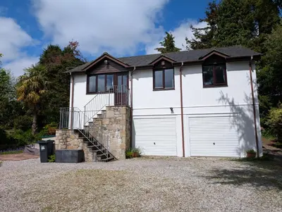 a white house with a garage at Near Eden Project apartment in Trethurgy