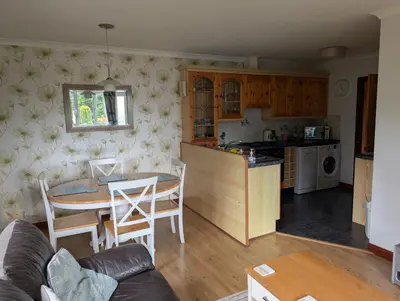 a kitchen and living room with a table and chairs at Near Eden Project apartment in Trethurgy