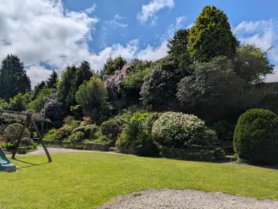 a garden with green grass and trees and bushes at Near Eden Project apartment in Trethurgy