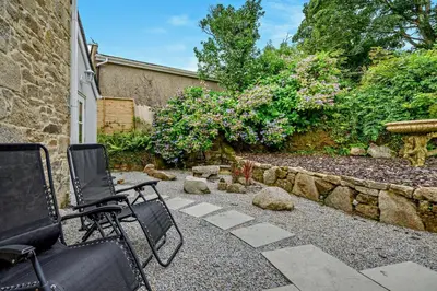 a patio with two chairs and a stone wall at 4 Bed in Penryn oc-c27969 in Penryn