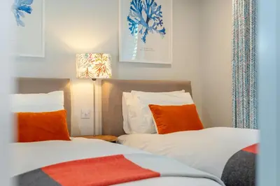 two beds with orange and white pillows in a room at 2 Bed in Padstow oc-h32002 in Padstow