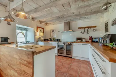 a large kitchen with white cabinets and wooden counter tops at 5 Bed in Tredethy oc-t31962 in Saint Mabyn
