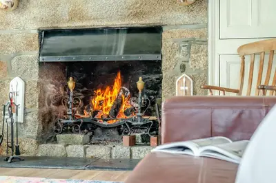 a fire in a stone fireplace with a book at 5 Bed in Tredethy oc-t31962 in Saint Mabyn