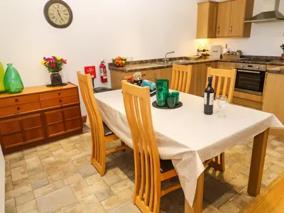 a kitchen with a table with chairs and a clock on the wall at The Baler House in Hayle