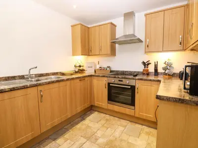 a kitchen with wooden cabinets and a sink at The Baler House in Hayle