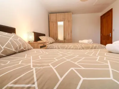 a bedroom with two beds and a window at The Baler House in Hayle