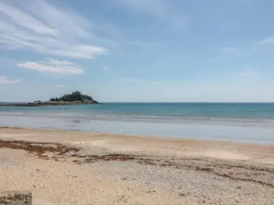 a beach with an island in the ocean at The Baler House in Hayle