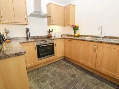 a kitchen with wooden cabinets and a sink at The Stable Barn in Hayle
