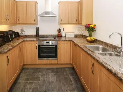 a kitchen with wooden cabinets and a sink at The Stable Barn in Hayle