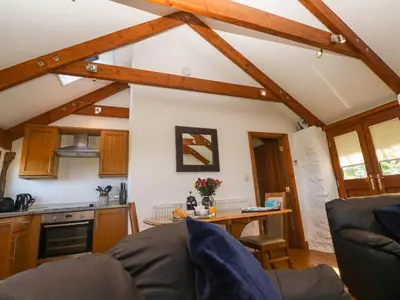 a living room with a table and a kitchen at Bay View Barn in Hayle