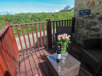 a bottle of wine and a vase of flowers on a deck at Bay View Barn in Hayle