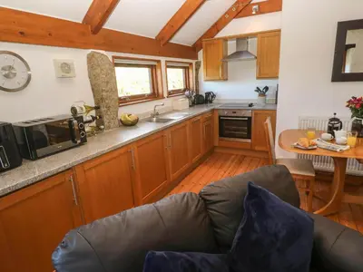 a kitchen with wooden cabinets and a couch in a room at Bay View Barn in Hayle