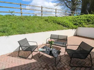 two chairs and a table on a brick patio at The Coach House in Hayle