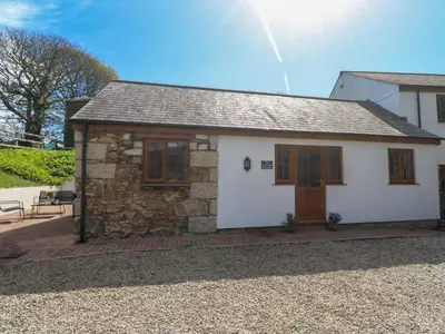 a small white house with a wooden door at The Coach House in Hayle