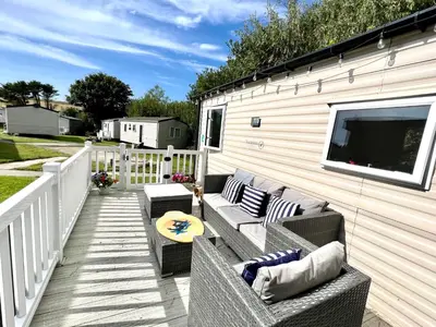 a patio with two couches and a television on a building at 3 Bedroom Caravan with Decking at Newquay Bay Resort in Porth