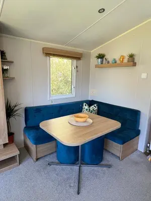 a table and a blue couch in a room at 3 Bedroom Caravan with Decking at Newquay Bay Resort in Porth