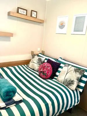 a bed with black and white striped sheets and pillows at 3 Bedroom Caravan with Decking at Newquay Bay Resort in Porth