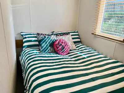 a bed with blue and white striped sheets and pillows at 3 Bedroom Caravan with Decking at Newquay Bay Resort in Porth