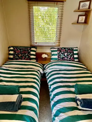 two beds sitting in a room with a window at 3 Bedroom Caravan with Decking at Newquay Bay Resort in Porth