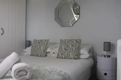 a bed with two pillows and a mirror on the wall at 4 St Eia - Happy Place in St Ives