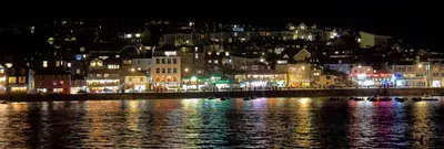 a city lit up at night next to a body of water at 4 St Eia - Happy Place in St Ives