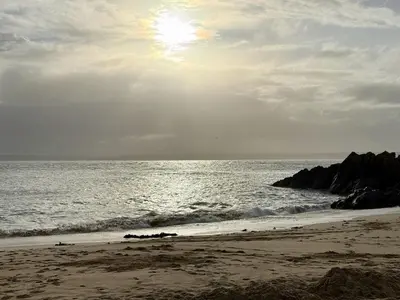 a beach with the sun rising over the ocean at 4 St Eia - Happy Place in St Ives
