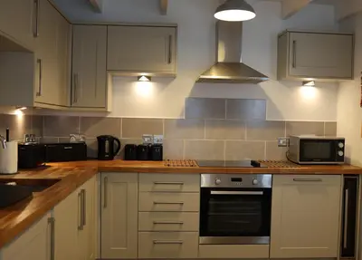 a kitchen with white cabinets and a stove top oven at 4 St Eia - Happy Place in St Ives