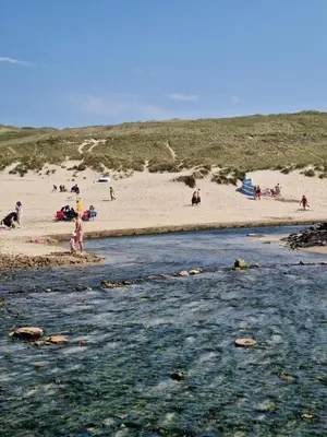 a group of people standing on the beach near a river at Dune Breeze-Haven Perran Sands Holiday Park in Perranporth